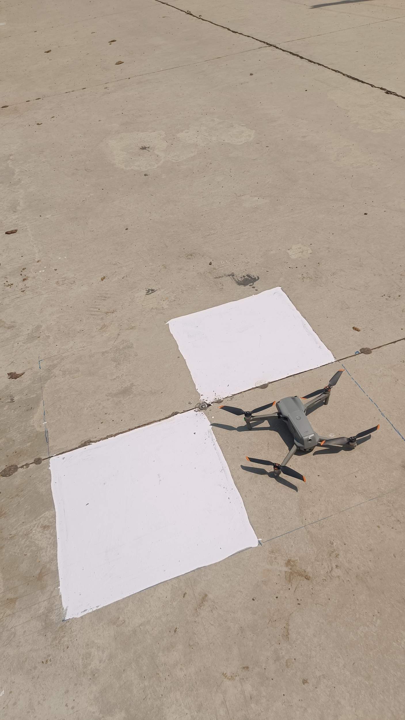 Drone prepared for takeoff near ground control point on flat pavement surface before stockpile survey