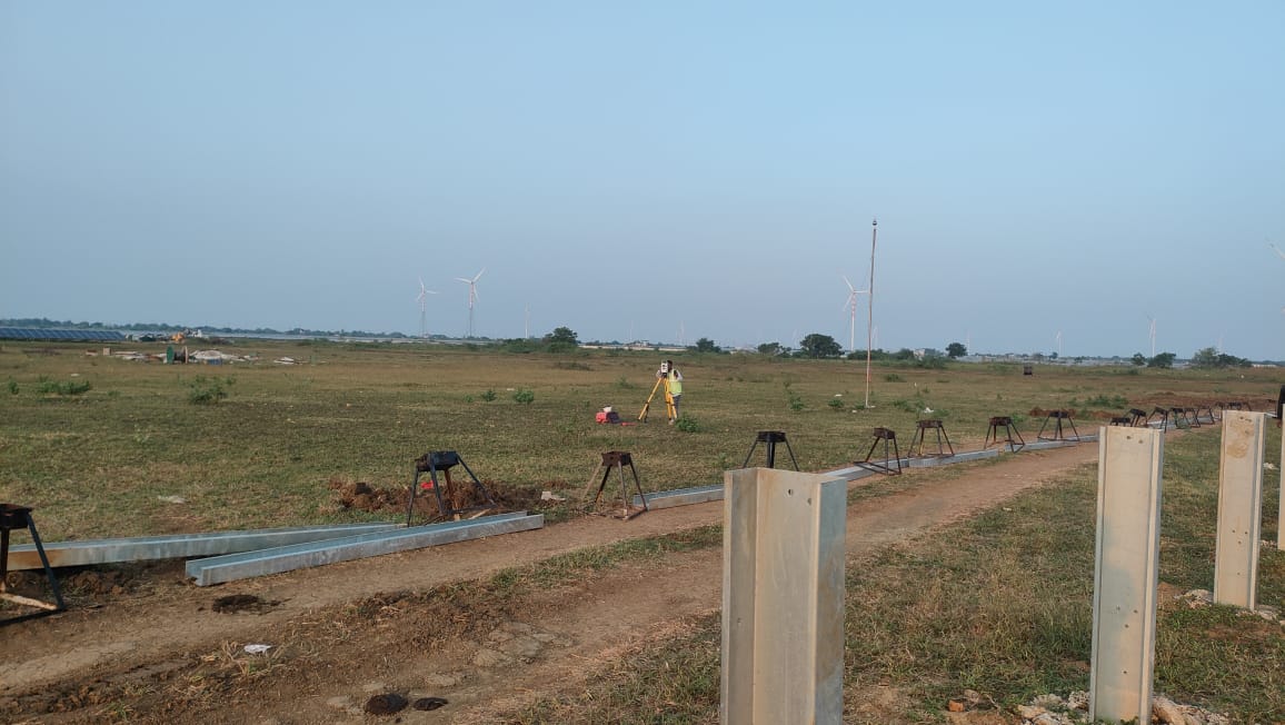 Total station operator taking readings on a large solar park survey site