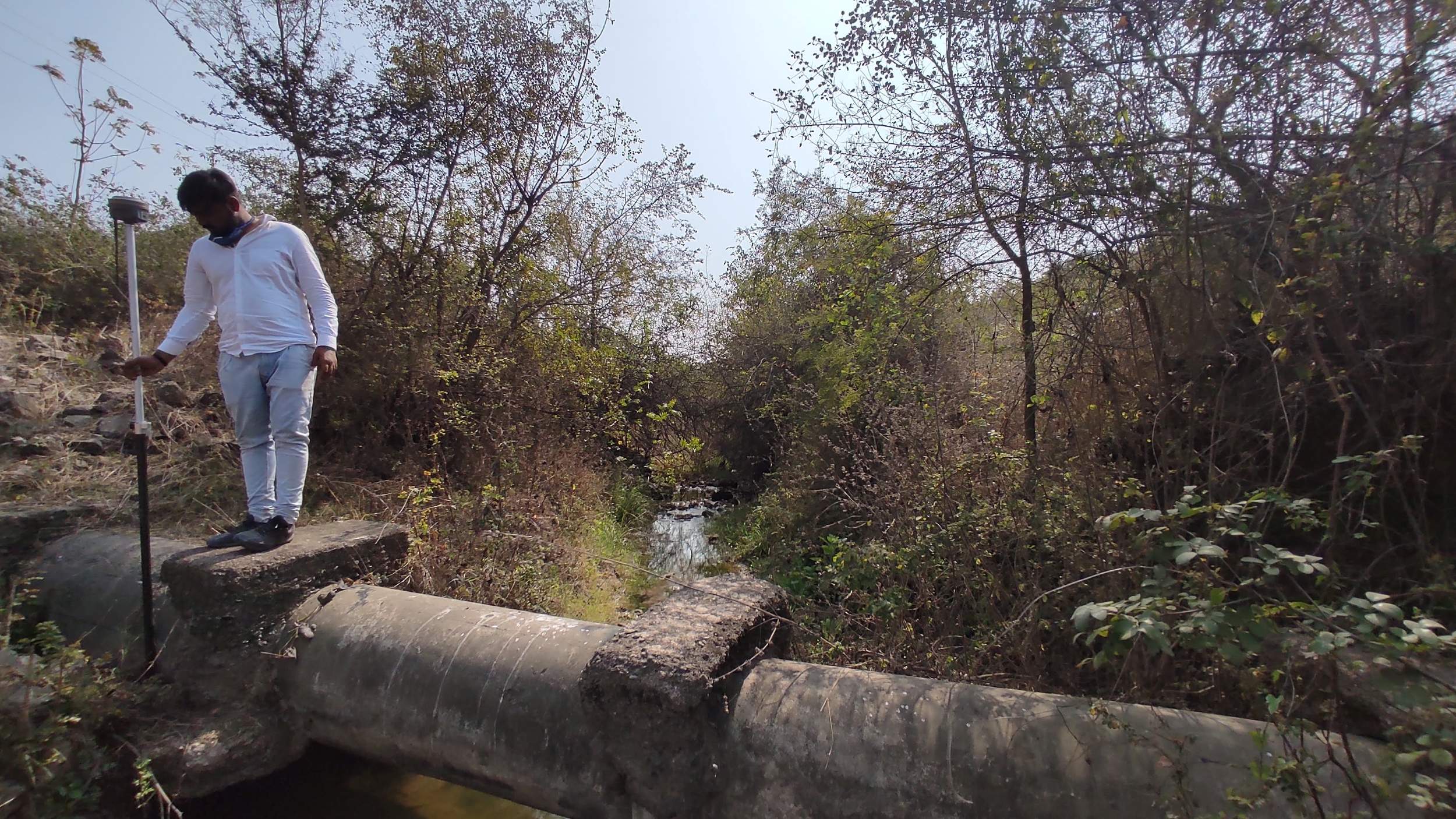 Surveyor taking DGPS reading from active natural water stream during canal network survey Gujarat